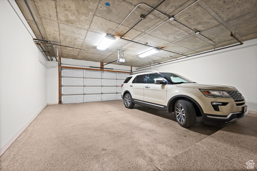 Parking garage with baseboards and a garage door opener