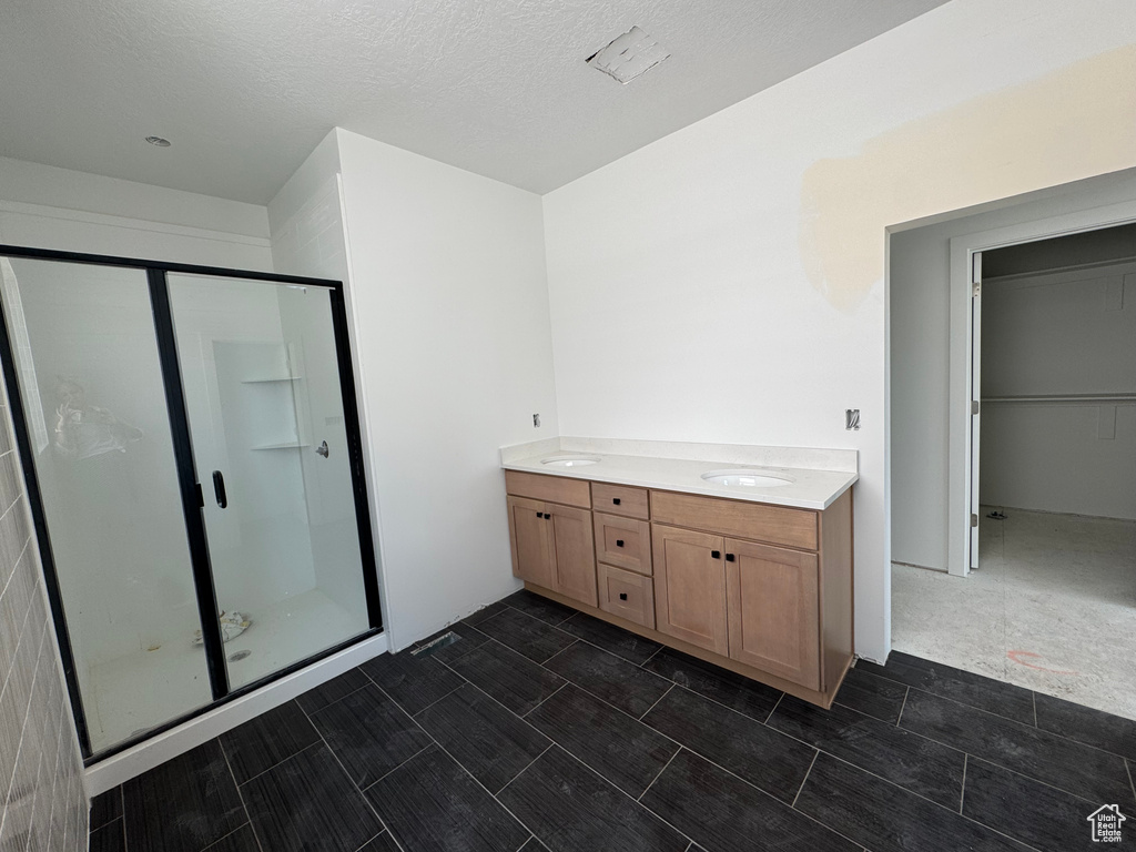 Bathroom with a shower stall, double vanity, and a walk in closet
