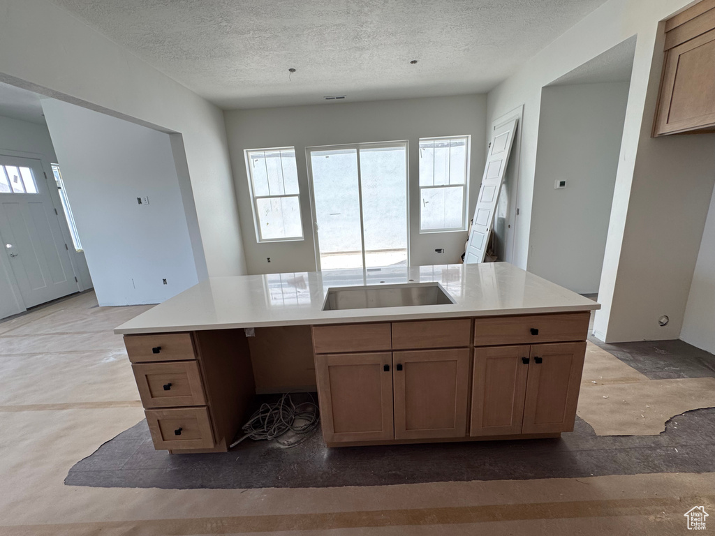 Kitchen featuring a textured ceiling, light countertops, and a center island