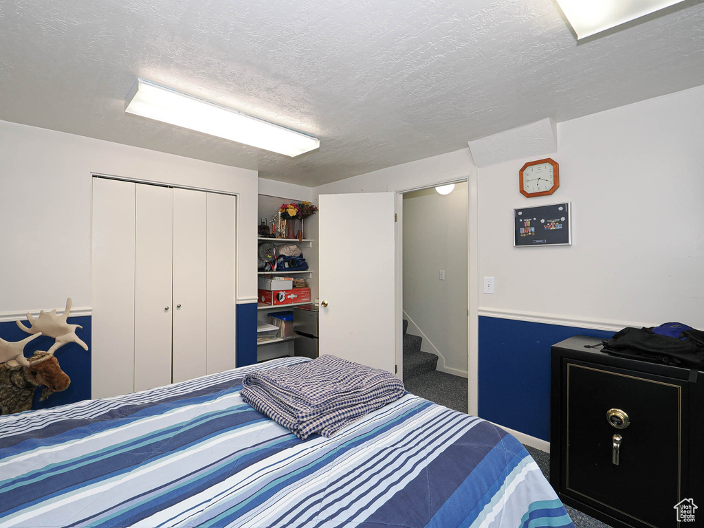 Bedroom with a closet, a textured ceiling, and carpet floors