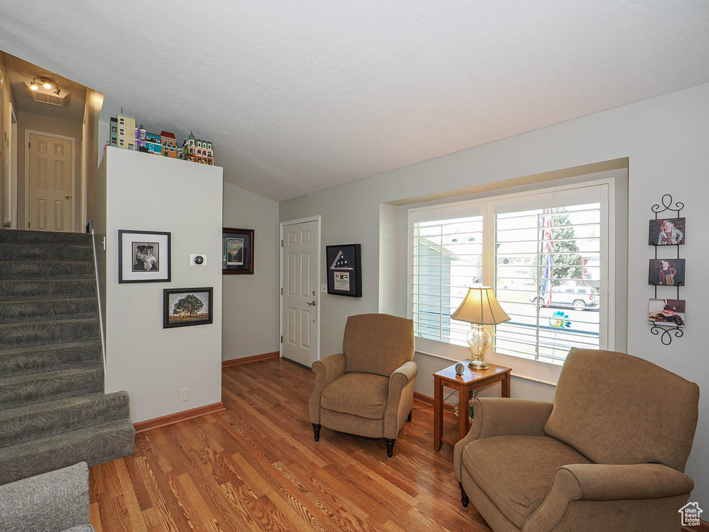 Living area with light wood-type flooring, stairs, vaulted ceiling, and baseboards