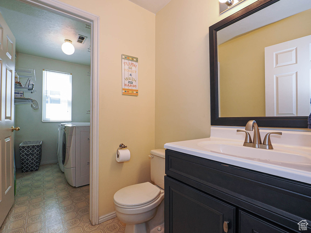 Bathroom with washer and dryer, toilet, vanity, baseboards, and tile patterned floors