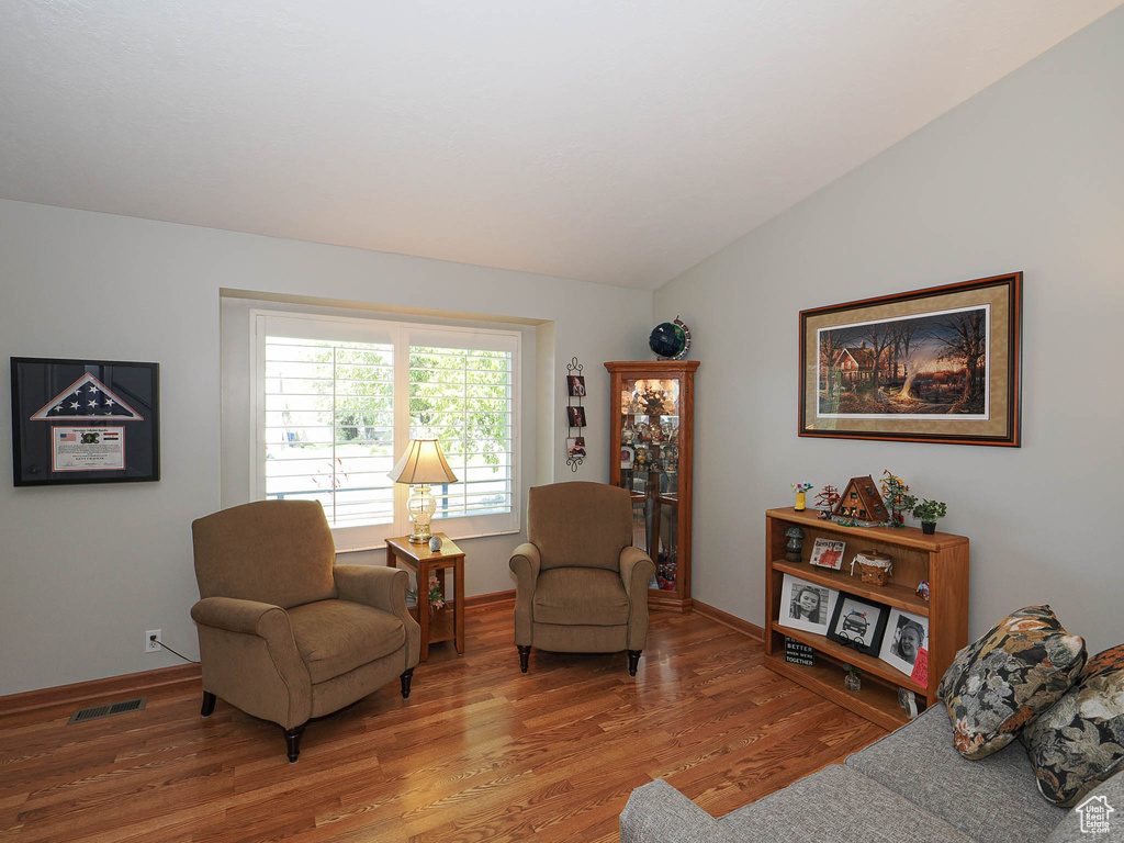 Living area featuring light wood-type flooring, baseboards, and lofted ceiling