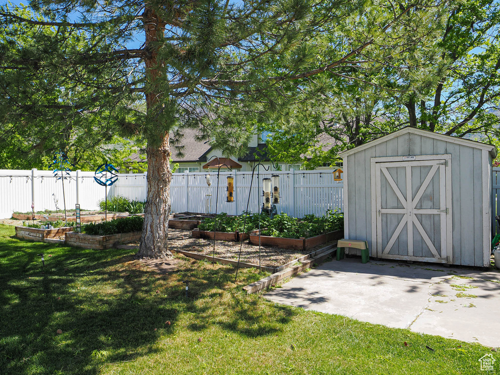 View of yard featuring a garden, a storage shed, and an outbuilding