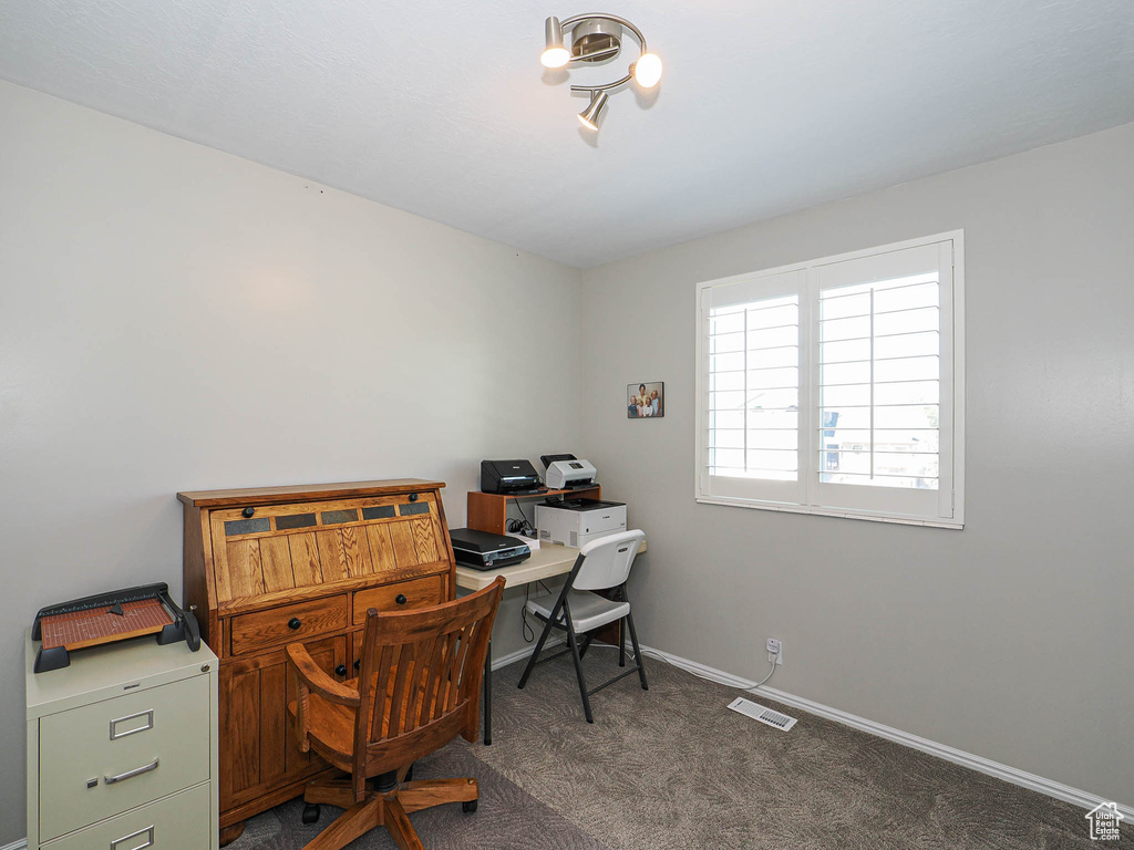 Office area featuring dark colored carpet and baseboards