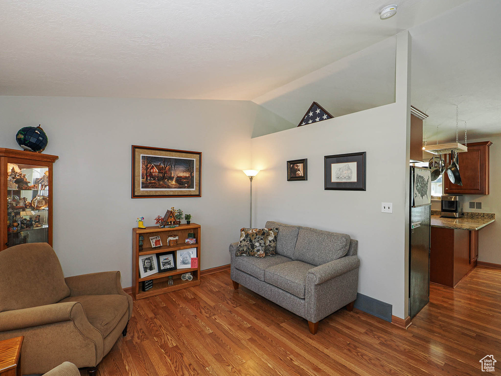 Living area with wood finished floors, vaulted ceiling, and baseboards