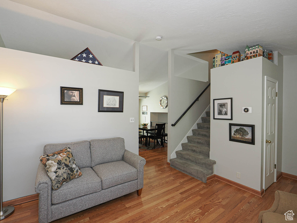 Living room with light wood-style flooring, stairway, and baseboards