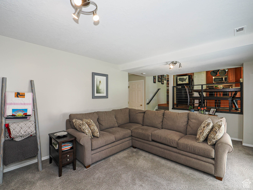 Living area featuring carpet flooring, stairway, and baseboards