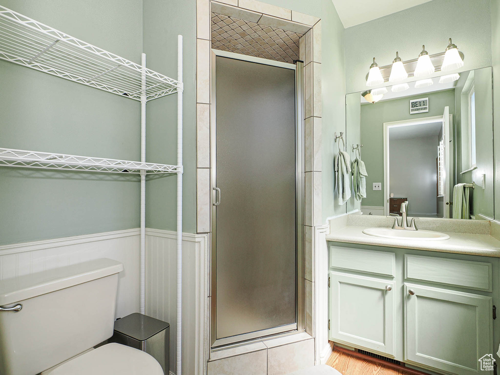 Full bath featuring a stall shower, toilet, vanity, and a wainscoted wall