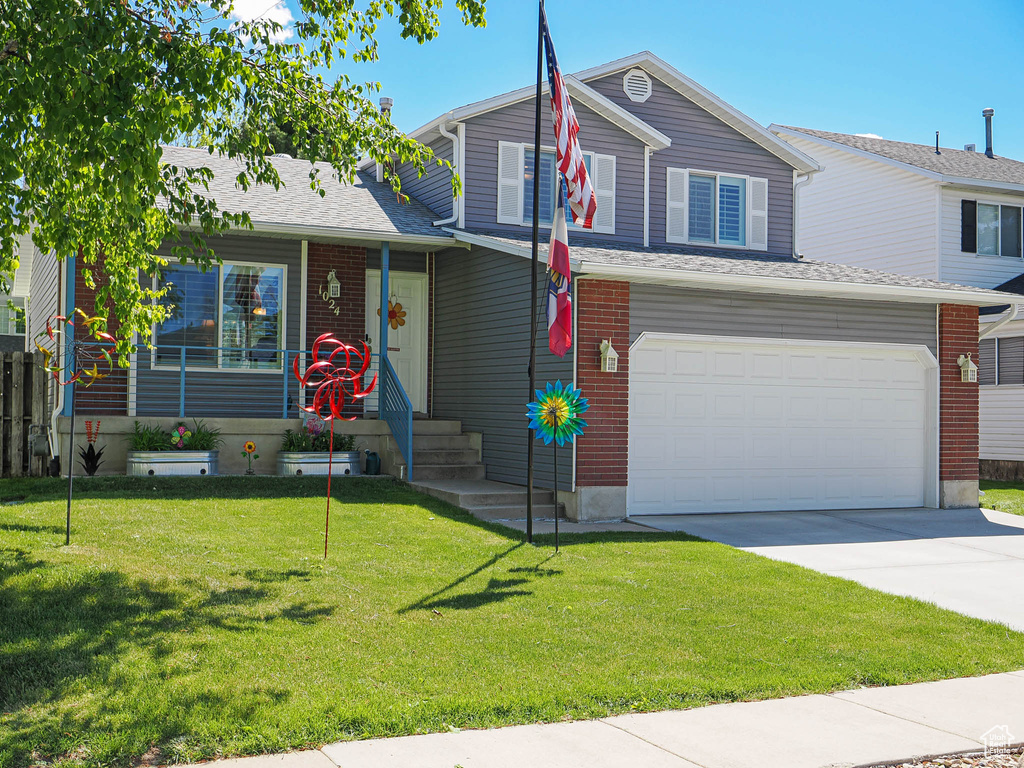 View of front facade with concrete driveway, a front lawn, and a garage