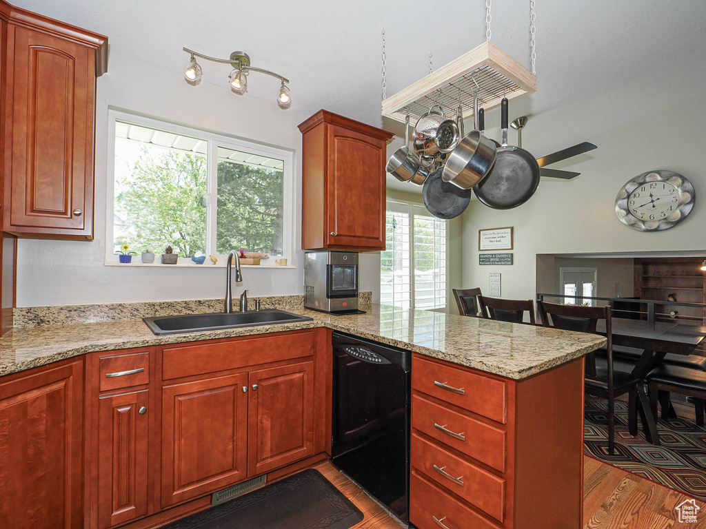 Kitchen with black dishwasher, a peninsula, a sink, ceiling fan, and wood finished floors