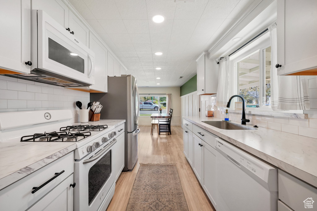Kitchen with white appliances, a sink, recessed lighting, light wood-style flooring, and light countertops