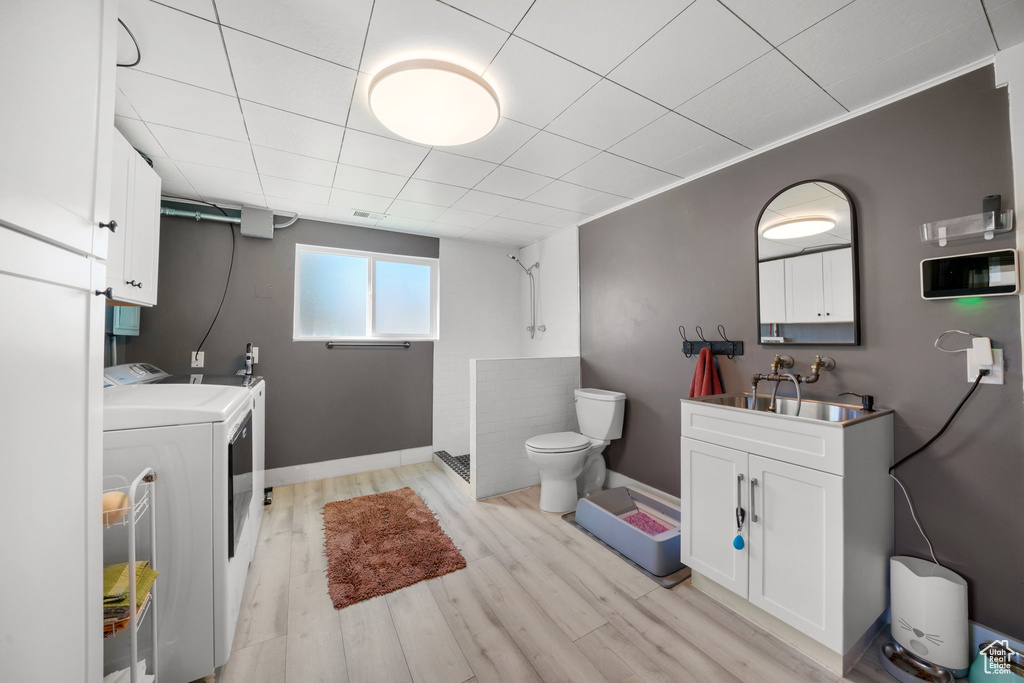 Full bath with washer and dryer, toilet, a shower, baseboards, and wood finished floors