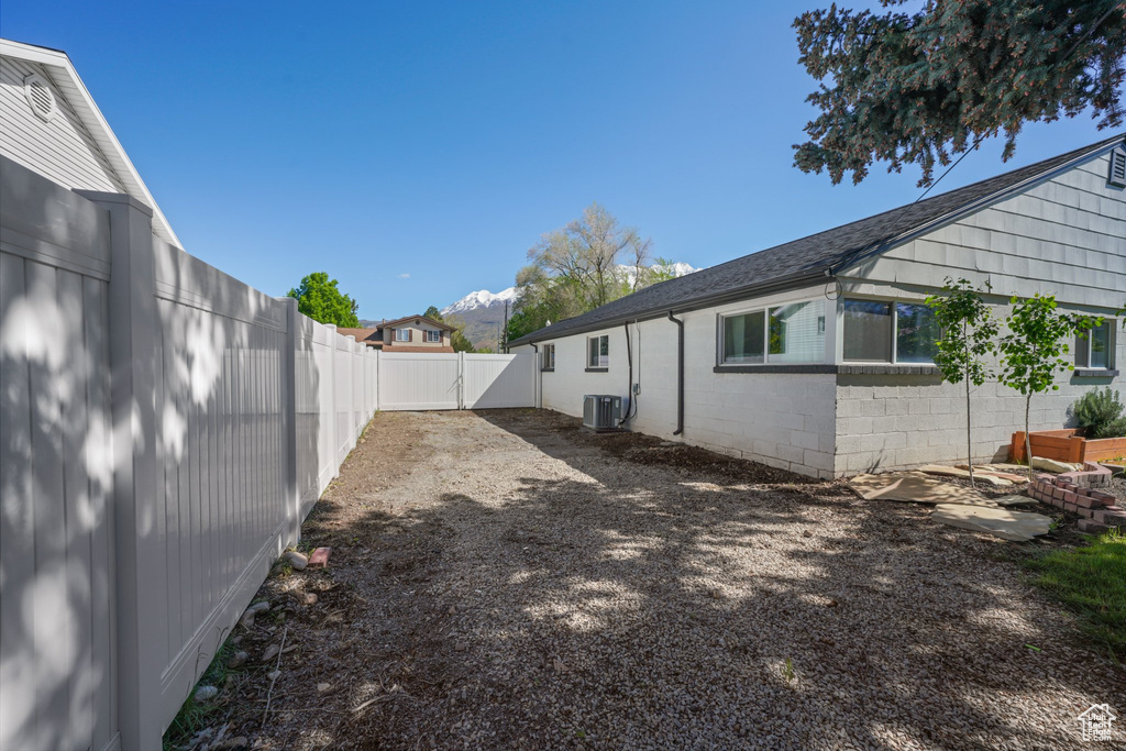 Fenced backyard featuring central AC and a gate