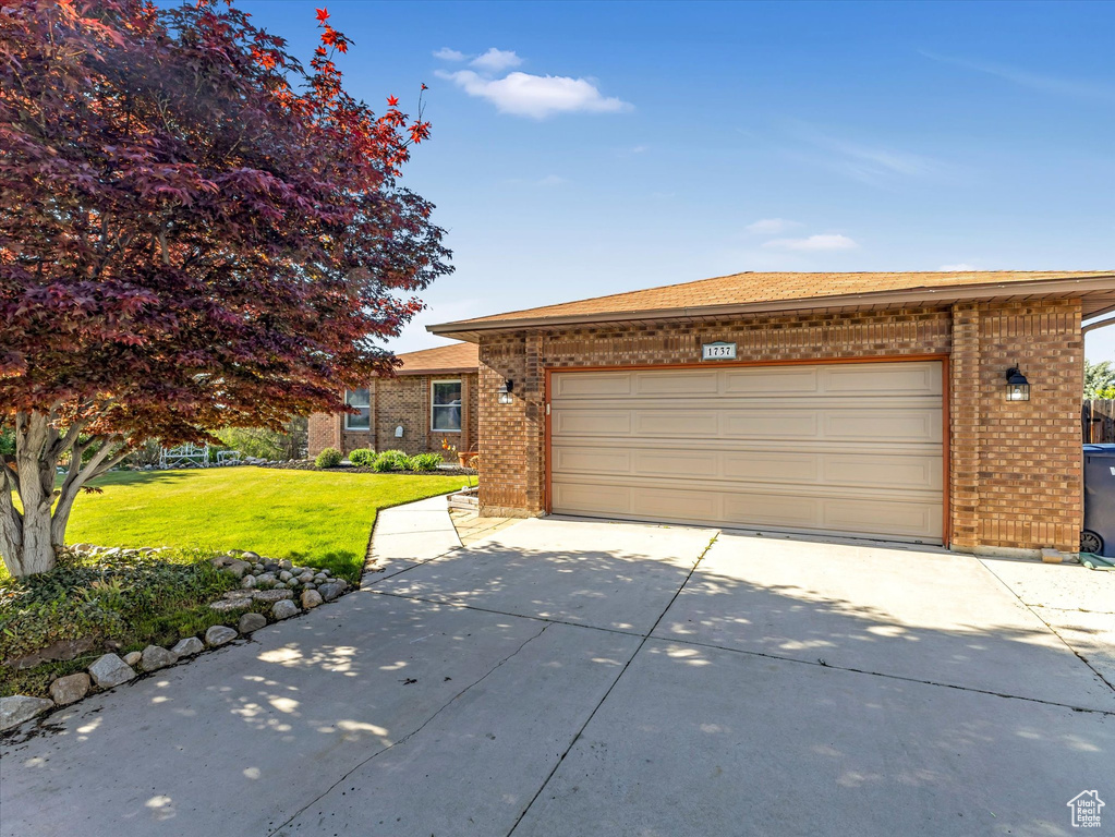 Ranch-style house featuring brick siding, driveway, a front lawn, and an attached garage