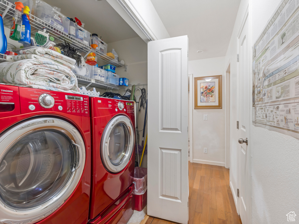 Clothes washing area with wood finished floors and separate washer and dryer