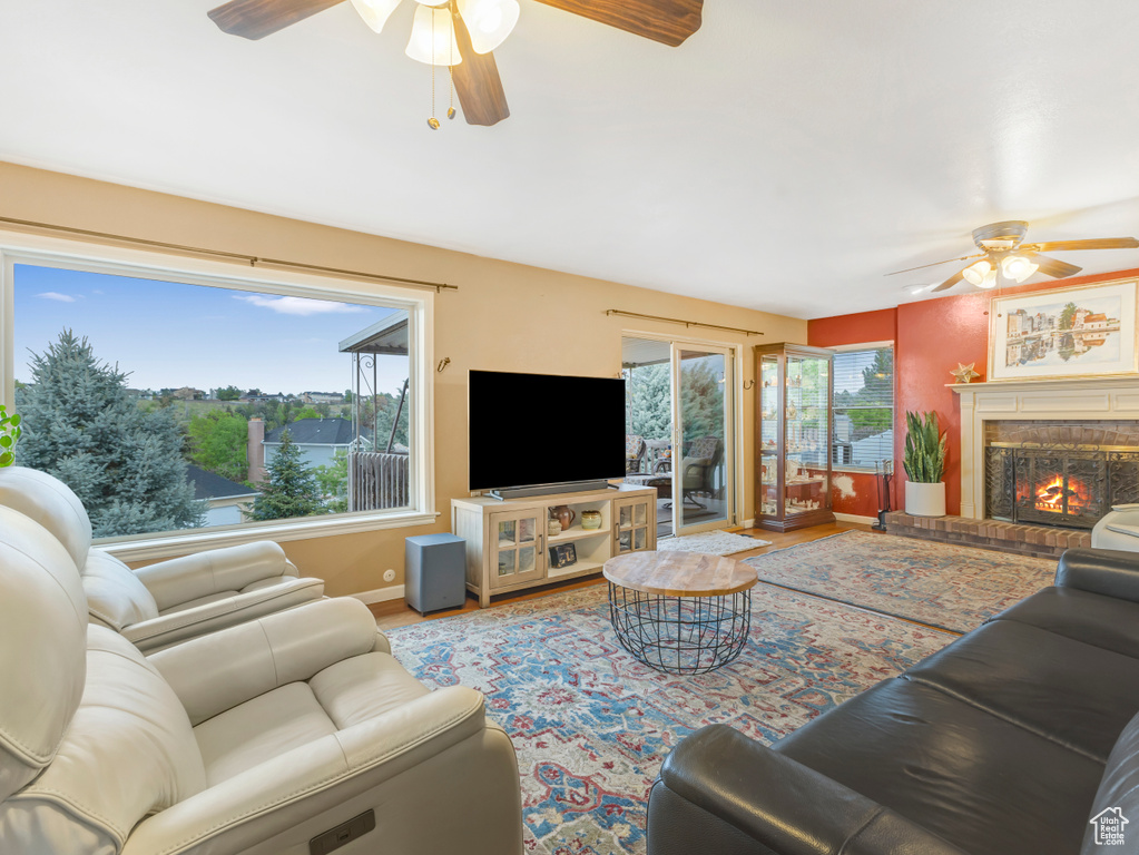 Living area with a ceiling fan, baseboards, wood finished floors, and a glass covered fireplace
