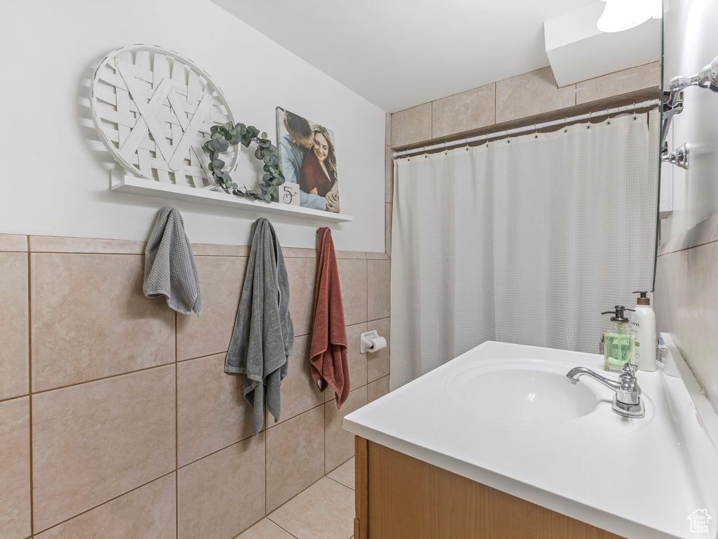 Bathroom featuring tile walls, curtained shower, vanity, wainscoting, and tile patterned flooring