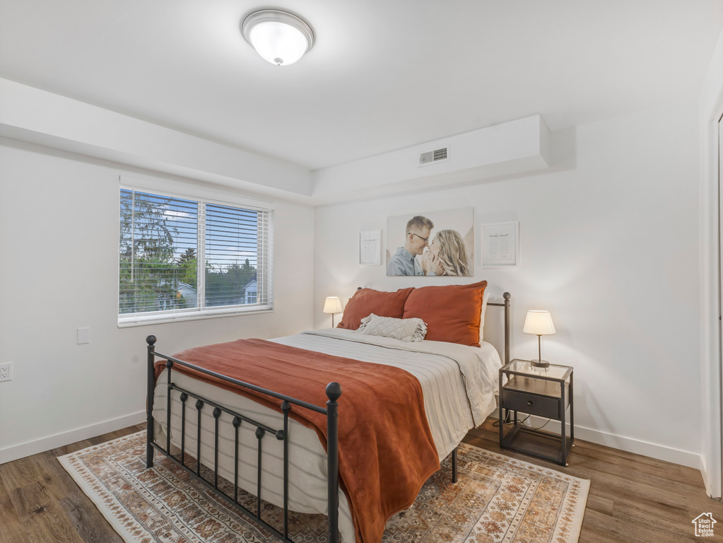 Bedroom featuring baseboards, wood finished floors, and a tray ceiling