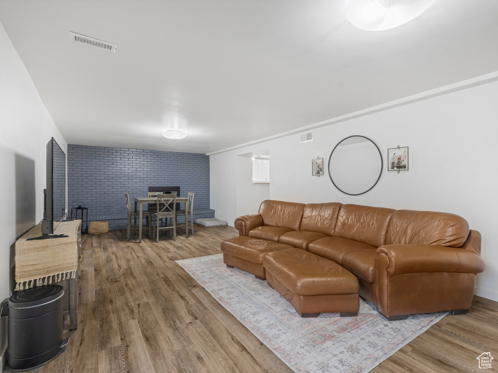 Living room with wood finished floors, brick wall, a wood stove, and an accent wall