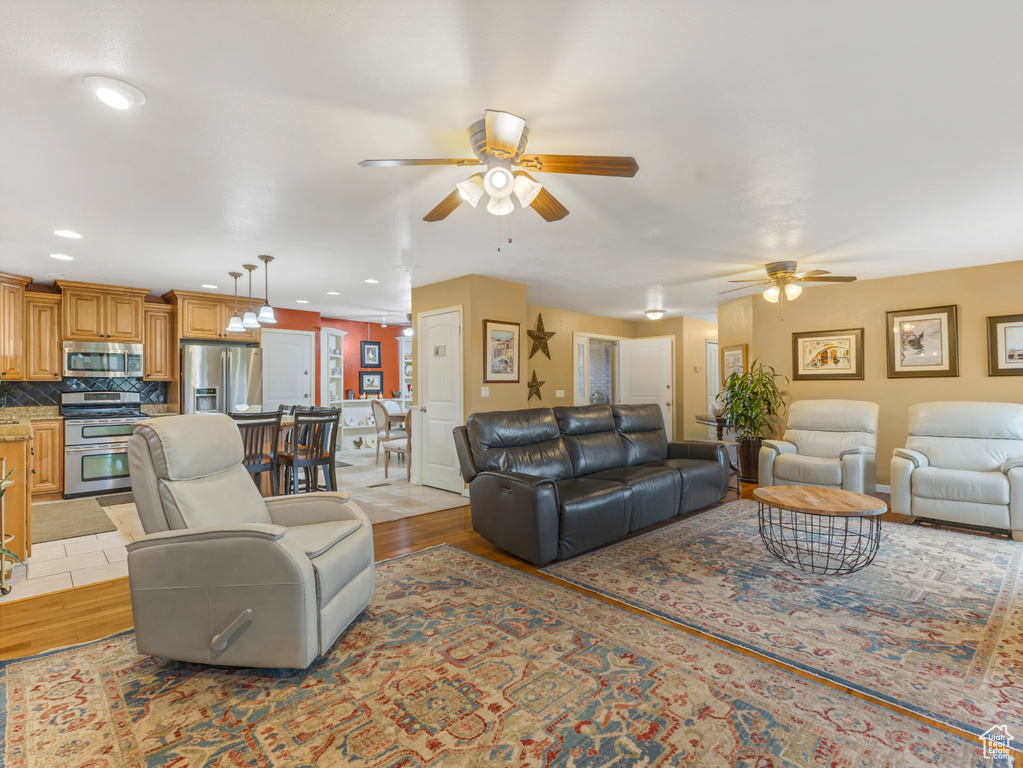 Living area with a ceiling fan, light wood-style flooring, and recessed lighting