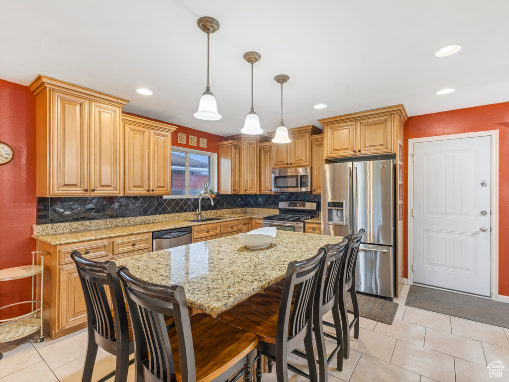 Kitchen with stainless steel appliances, a sink, decorative backsplash, light stone counters, and light tile patterned flooring