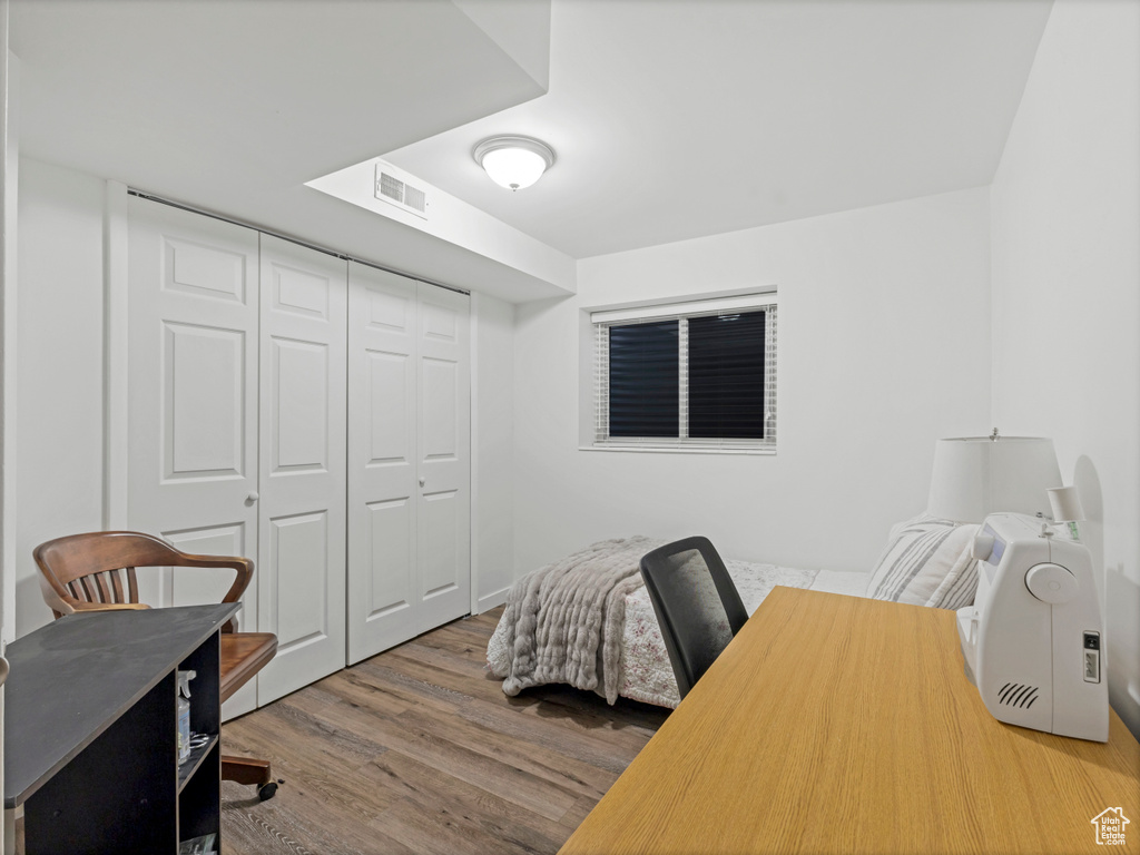 Bedroom with wood finished floors and a closet