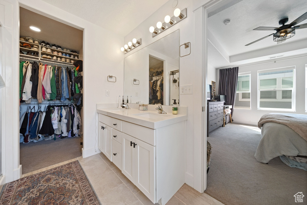 Full bathroom with a ceiling fan, double vanity, a walk in closet, ensuite bathroom, and tile patterned flooring