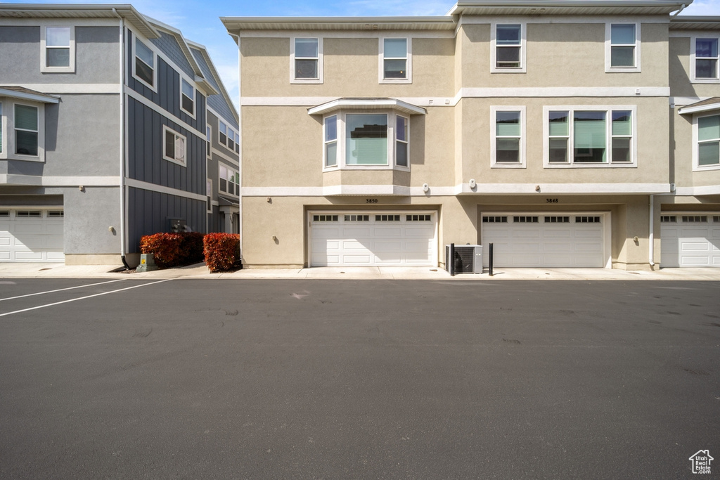 Townhome / multi-family property featuring stucco siding, a garage, and central AC unit