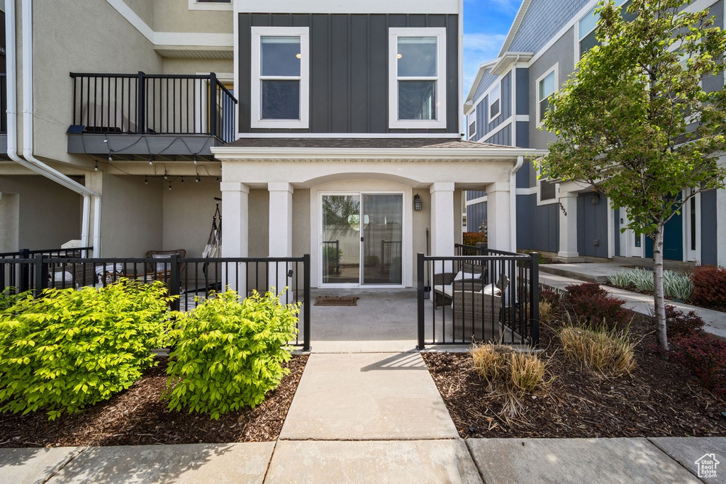 Property entrance featuring a balcony, stucco siding, a porch, and board and batten siding