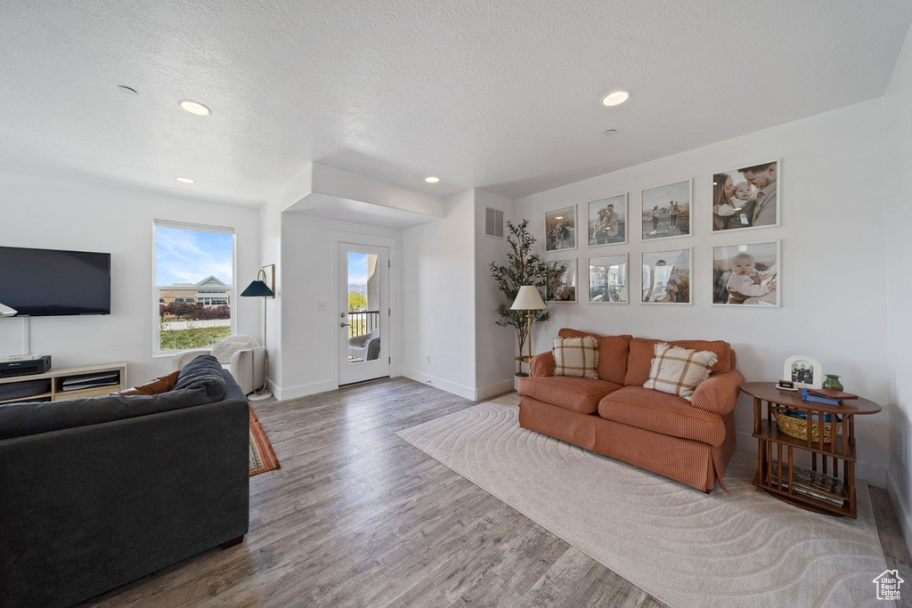 Living area with wood finished floors, recessed lighting, and baseboards