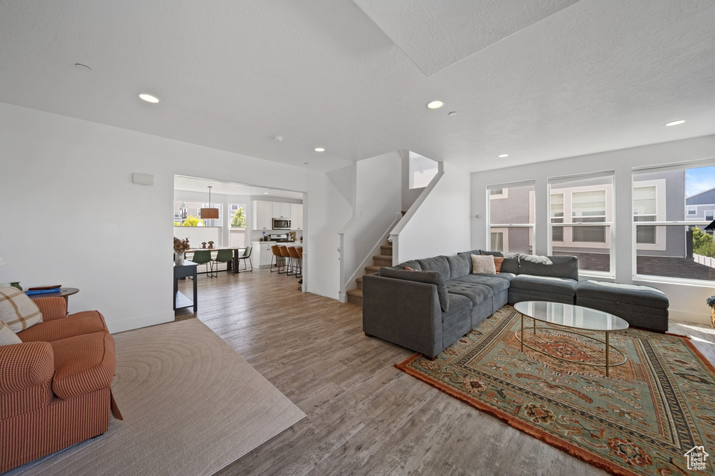 Living room with stairs, wood finished floors, recessed lighting, and baseboards