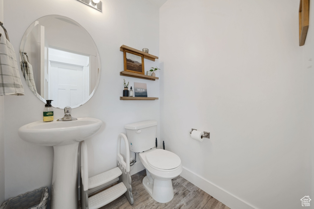 Half bath with toilet, wood finished floors, and baseboards