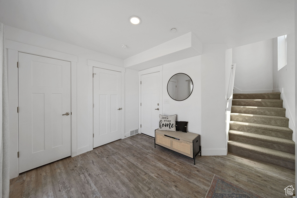 Foyer entrance featuring wood finished floors, stairway, and baseboards