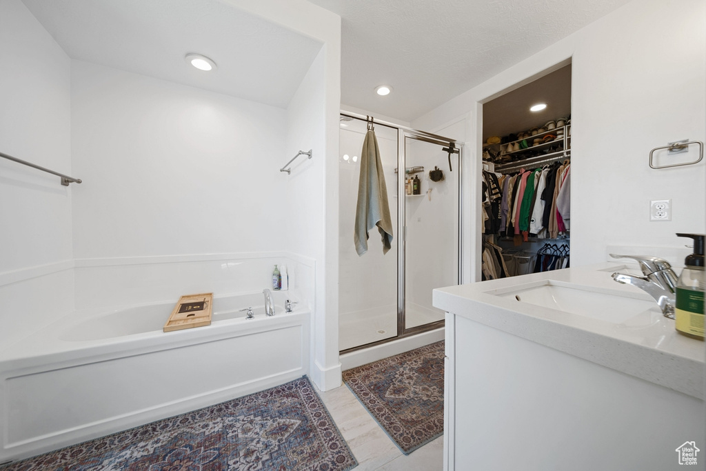 Full bathroom with a sink, a stall shower, a walk in closet, a bath, and recessed lighting