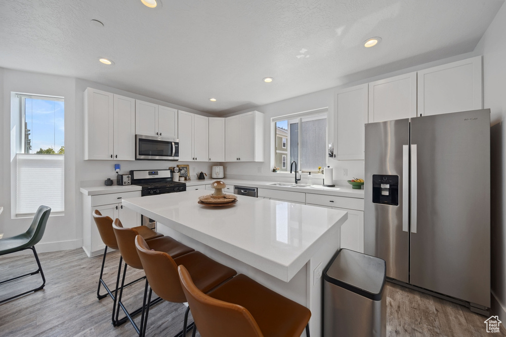 Kitchen with stainless steel appliances, a sink, plenty of natural light, a breakfast bar area, and recessed lighting
