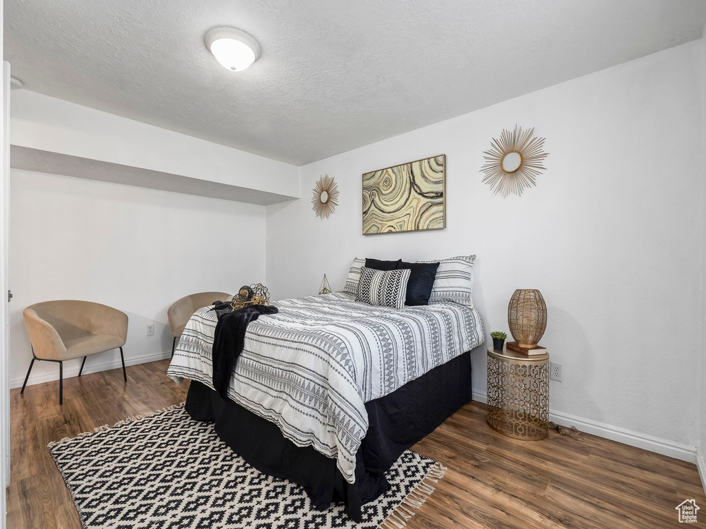 Bedroom featuring wood finished floors, baseboards, and a textured ceiling