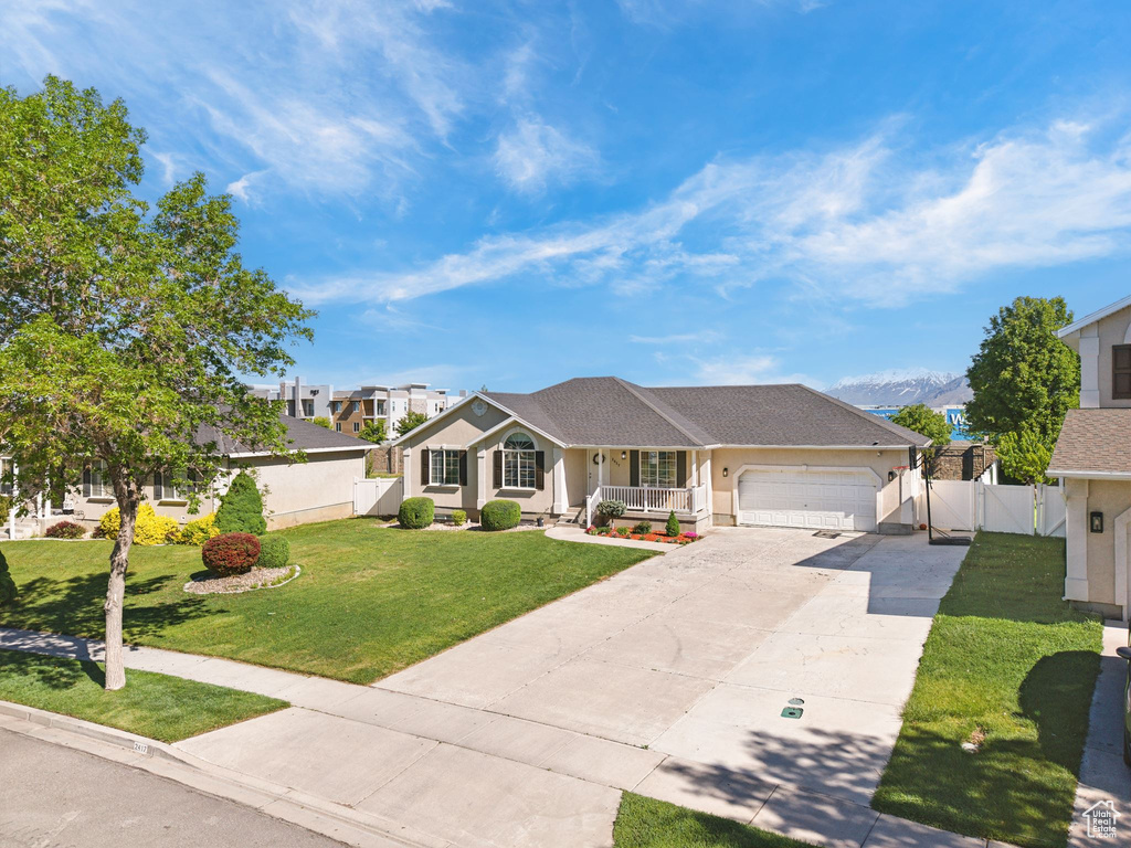 Ranch-style house featuring covered porch, a garage, driveway, stucco siding, and a gate