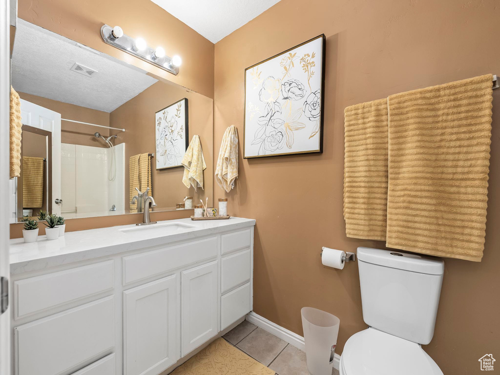 Bathroom featuring tile patterned flooring, toilet, a shower, vanity, and baseboards