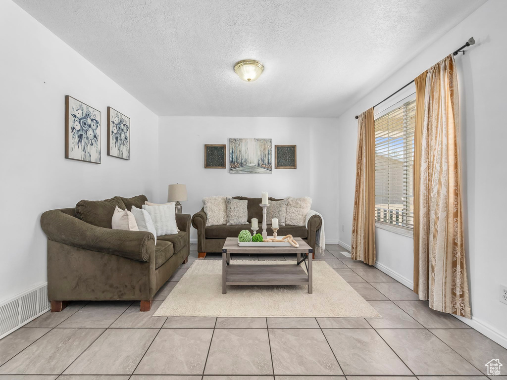 Living room featuring a textured ceiling and light tile patterned floors