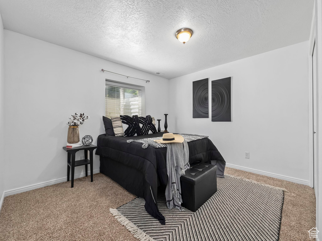 Carpeted bedroom featuring a textured ceiling and baseboards