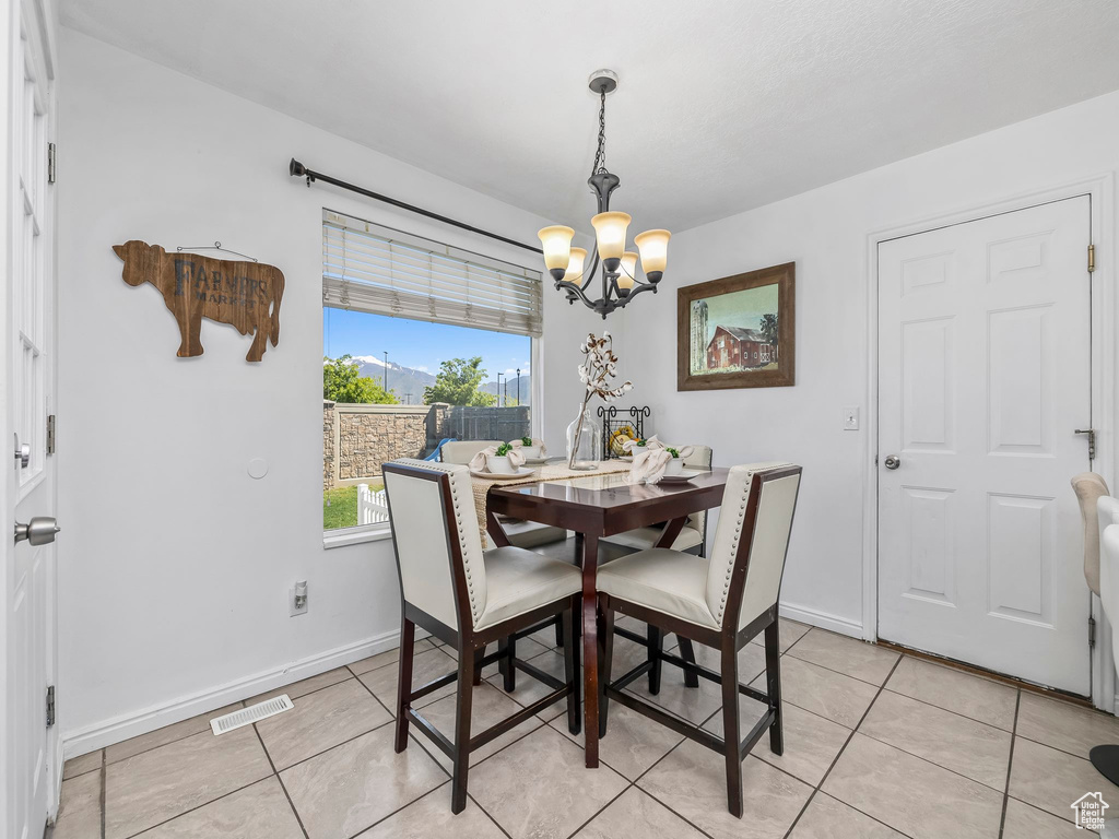Dining space featuring a chandelier, light tile patterned floors, and baseboards