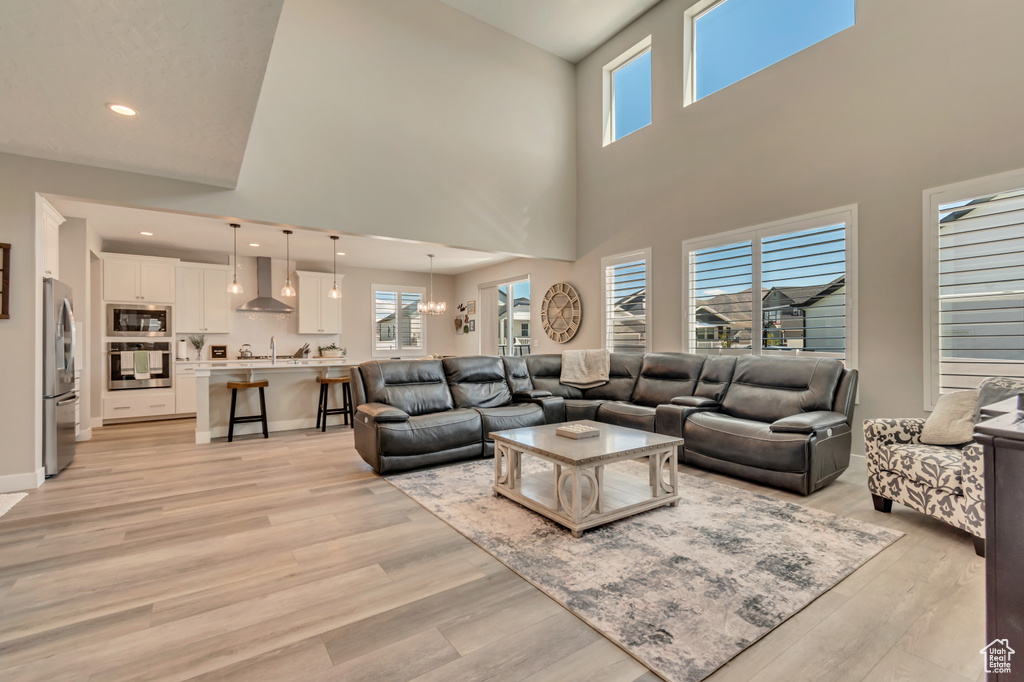 Living room with a high ceiling, healthy amount of natural light, light wood finished floors, and recessed lighting