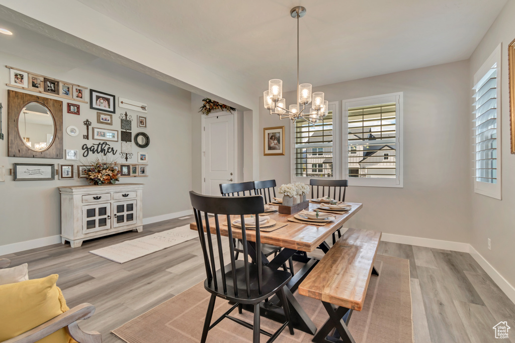 Dining space with a chandelier, wood finished floors, and baseboards