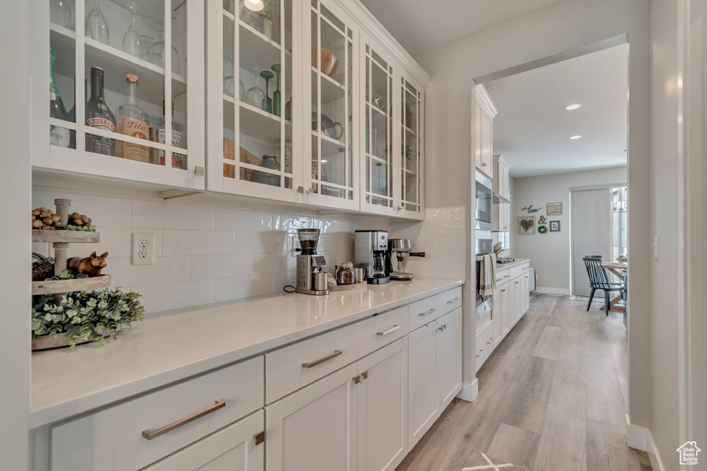 Bar area with backsplash, light wood-style flooring, baseboards, and recessed lighting