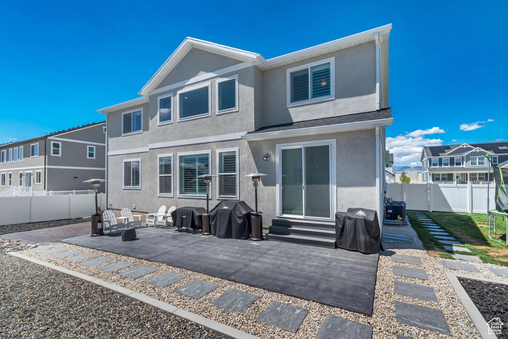 Back of house with stucco siding, a patio area, a fenced backyard, and entry steps