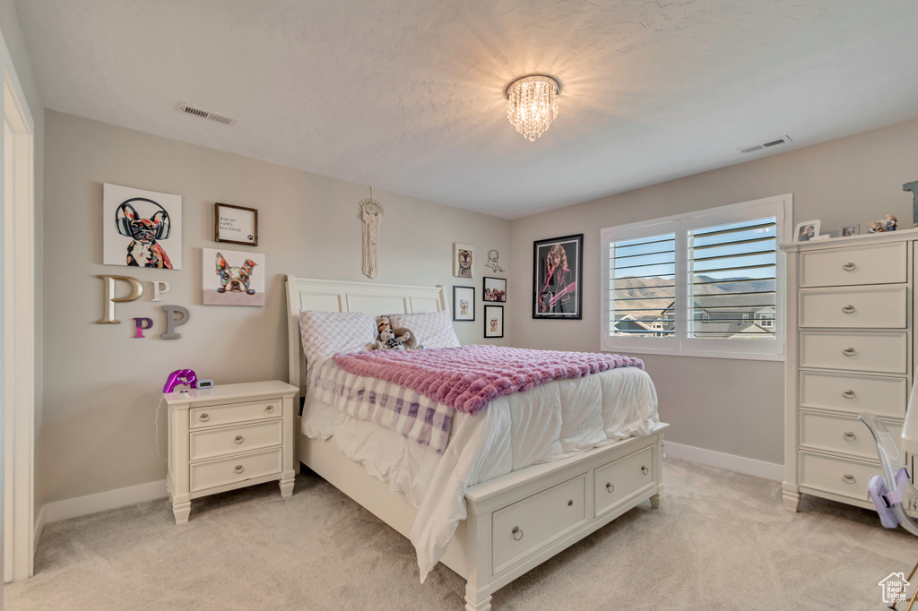 Bedroom with light colored carpet, baseboards, and a chandelier