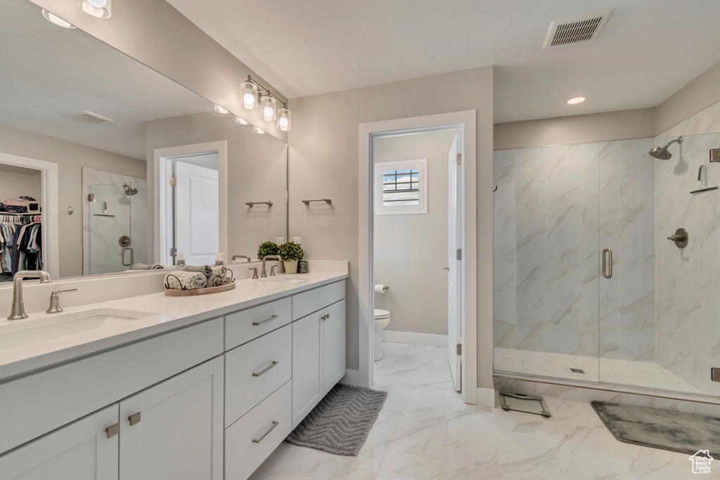 Full bath with toilet, a marble finish shower, marble finish flooring, double vanity, and recessed lighting