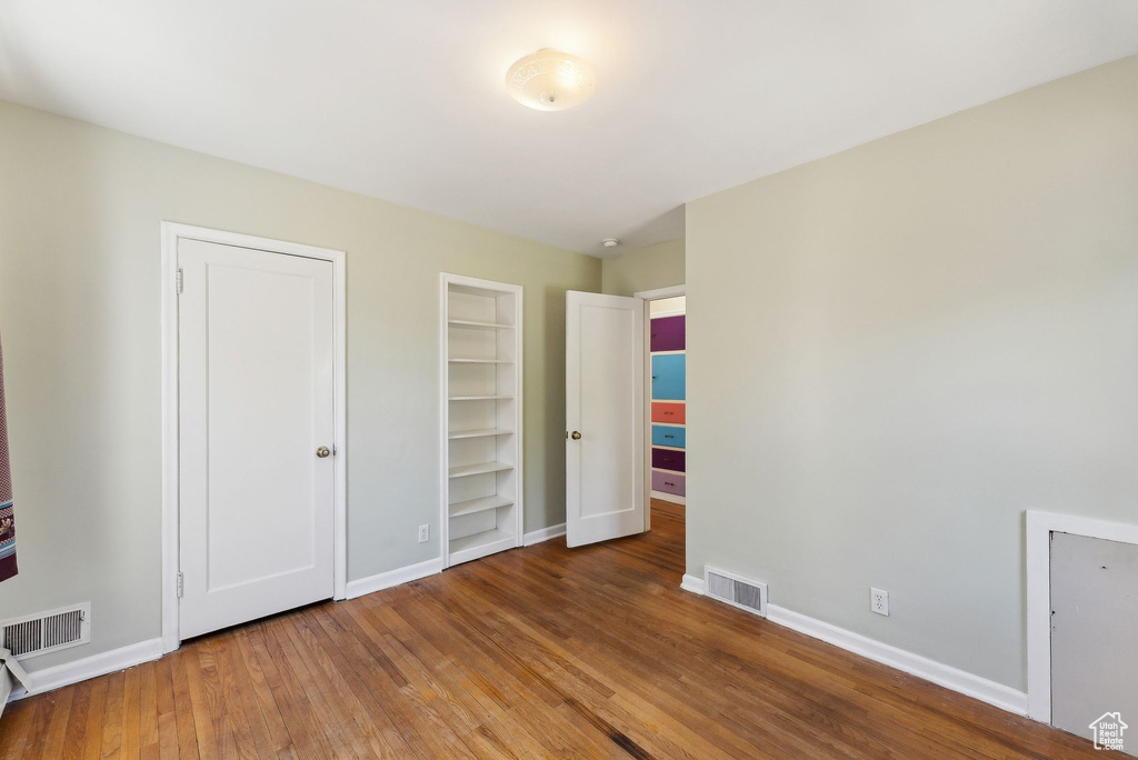 Unfurnished bedroom featuring wood finished floors and baseboards