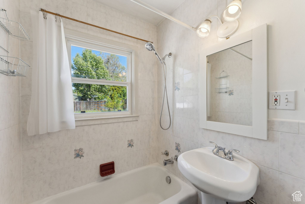 Bathroom featuring a sink, shower / bathtub combination, and tile walls